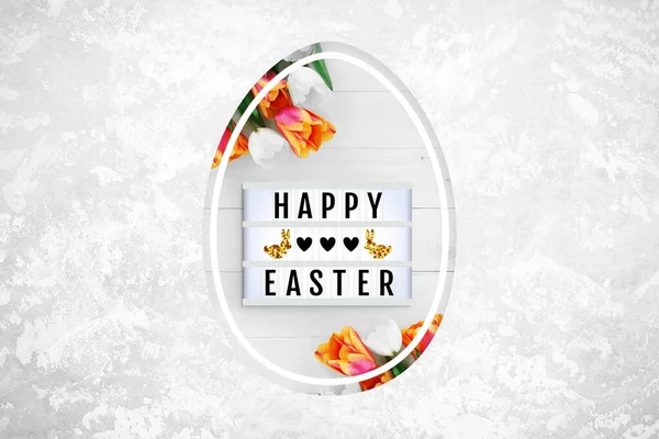 Lightbox and flowers in Easter egg shaped hole on a light concrete background. Text frame of the lightbox with the inscription Happy Easter, hearts, bunnies. Top view, close up, copy space