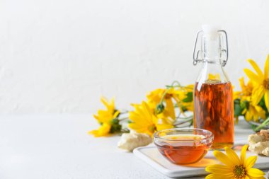 Şişe, çiçek ve kök içinde Kudüs enginar şurubu.