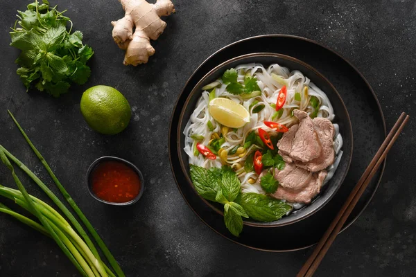 Pho Bo Soep met rundvlees in kom op zwarte achtergrond. Vietnamese keuken. — Stockfoto