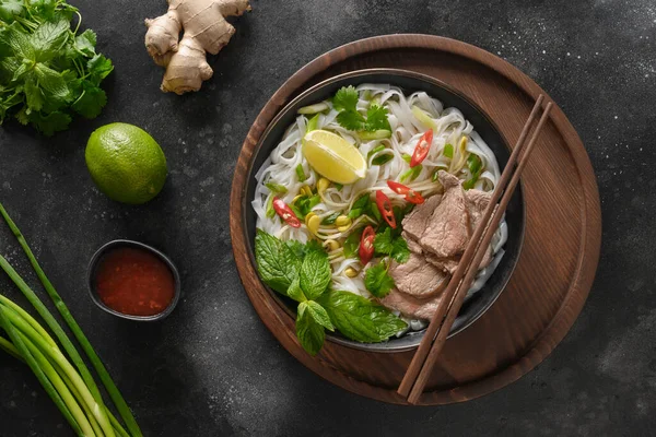 Pho Bo Sopa con carne de res en tazón sobre fondo negro. Cocina vietnamita. — Foto de Stock