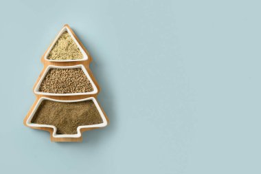 Kenevir tohumu, un, mavi arka planda noel ağacı şeklinde çekirdekler. Eko tebrik kartı. Yemek tatili konsepti. Alternatif yaratıcı Xmas ağacı. Üst görünüm.