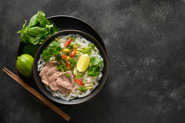 Pho Bo Sopa con carne de res en tazón sobre fondo negro. Cocina vietnamita. —  Fotos de Stock