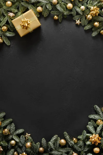 黄金の贈り物、泡、黒の背景に常緑の枝を持つクリスマスの垂直フレーム。クリスマスグリーティングカード. — ストック写真