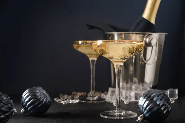 Πρωτοχρονιά σαμπάνια σε ποτήρια κρασιού και μπουκάλι σε κουβά διακοσμημένα Χριστούγεννα μπλε μπιχλιμπίδια. — Φωτογραφία Αρχείου