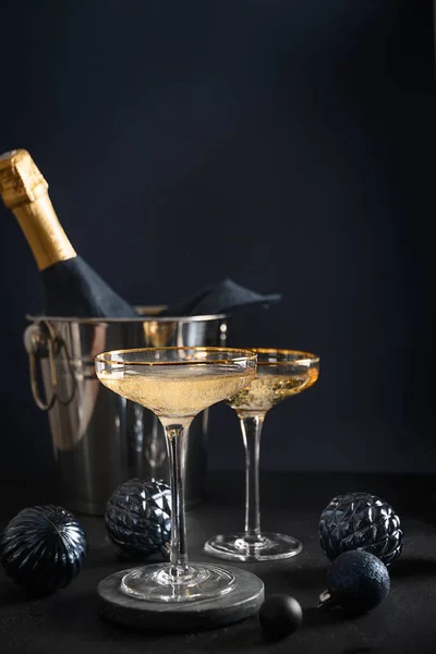 Γιορτινή σαμπάνια σε ποτήρια κρασιού και χριστουγεννιάτικα μπλε μπιχλιμπίδια σε σκούρο φόντο. 2022 Πρωτοχρονιάτικο πάρτι — Φωτογραφία Αρχείου