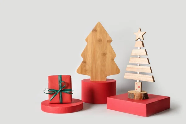 Рождественские елки на красной стойке с подарком на сером фоне. Рождественские открытки. — стоковое фото