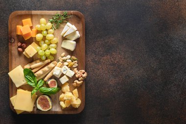 Üzümlü peynir tabağı, fındık, kahverengi arka planda incir. Üst Manzara. Bayram için gurme aperatifi.