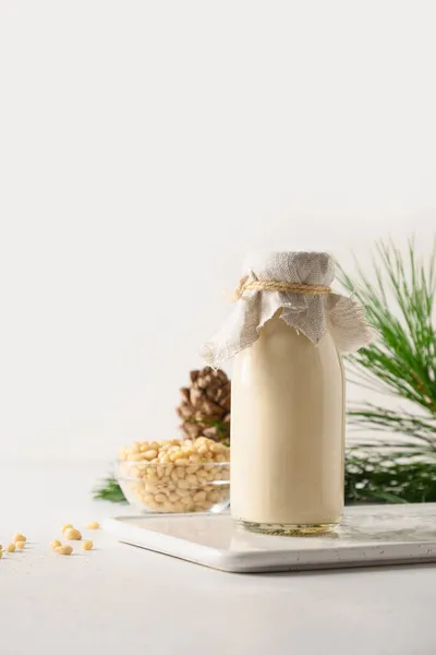Zedernussmilch und Nüsse auf weißem Hintergrund. Alternative Milch auf Pflanzenbasis. — Stockfoto