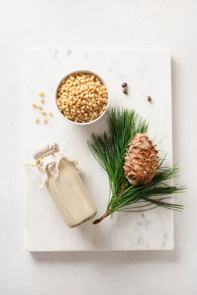 Zedernussmilch und Nüsse auf weißem Hintergrund. Alternative Milch auf Pflanzenbasis. — Stockfoto