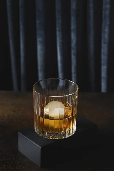 Kall whisky serveras i stenar på mörkblå gardin trendig bakgrund. Vertikalt format. Närbild. — Stockfoto