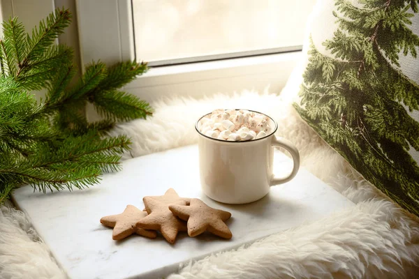 Winter coffee with marshmallow on cozy window sill with Christmas fir branches.