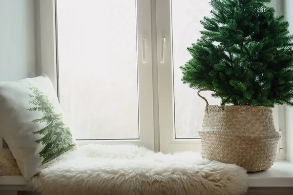 Winter gemütliche Fensterbank mit Weihnachtsbaum in Weidenkorb, Kissen, Fellhaut. Weihnachtsferien. — Stockfoto