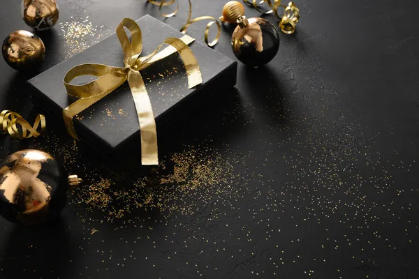 Stock image Gold and black gift and baubles with Christmas decorations.