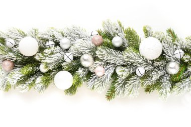 Beyaz süs eşyalarıyla süslenmiş Noel çelengi beyaz arka planda karlı ve yeşil köknar dalları. Geniş boyut.