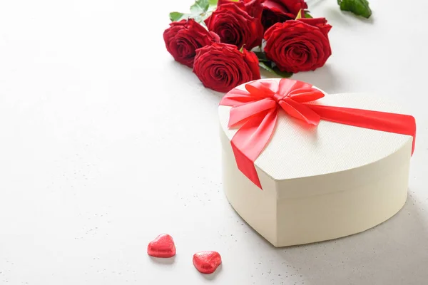 Подарок на день Святого Валентина, красные шоколадные конфеты и красные розы на белом . — стоковое фото