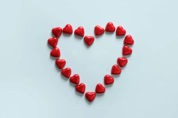 Романтические шоколадные конфеты как сердце в красной фольге и текст на деревянных блоках - Любовь в белой тарелке. — стоковое фото