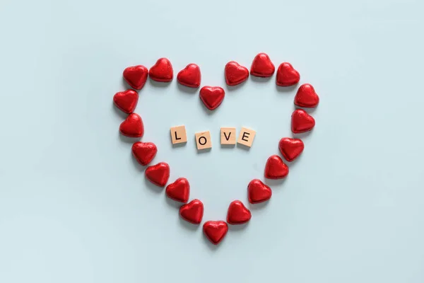 Романтические шоколадные конфеты как сердце в красной фольге и текст деревянных блоков - Любовь. — стоковое фото