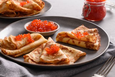 Gri masadaki kırmızı havyarlı ince Rus krepleri..