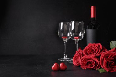 Valentine's day dating with red wine, bouquet of red roses on black background. Invitation or greeting card. Copy space.