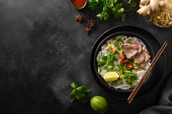 Pho Bo Soep met rundvlees in kom op zwarte achtergrond. Vietnamese keuken. — Stockfoto