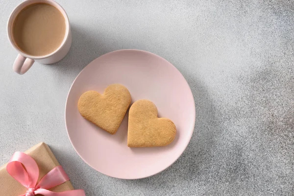 Herzförmige Kekse auf rosa Teller mit Kaffee und Geschenk zum Valentinstag. — Stockfoto