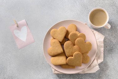 Pembe tabakta kalp şeklinde kurabiyeler. Sevgililer Günü için kahve ve hediye..