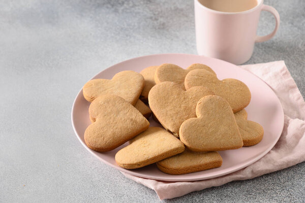 Valentines Day coffee with milk and heart shaped cookies on pink plate.