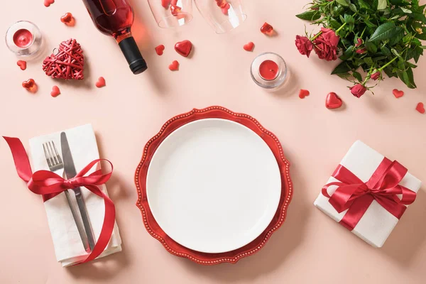 Walentynki miejsce stół nakrycie prezentem, butelka czerwonego wina, róże, serca. — Zdjęcie stockowe