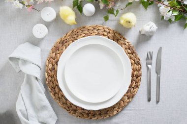 Sarı civcivli Paskalya masası, yumurtalar, gri keten masa örtüsü üzerinde taze çiçekler..