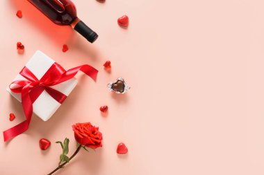 Romantik hediyeli sevgililer günü kartı, kırmızı şarap, kalpler çikolatalı tatlı ve pembe arka planda gül. Yukarıdan bak. Selamlarınız için yer açın..