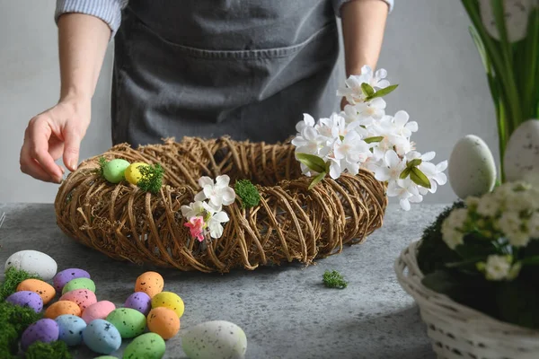 Mujer haciendo corona floral de Pascua de materiales naturales de flores y huevos. — Foto de Stock