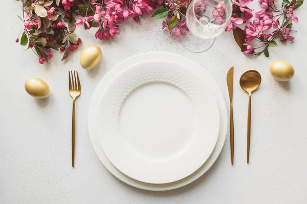 Великодня вечеря з яйцями, кроликом, святковим посудом і тюльпанами на білому . — стокове фото
