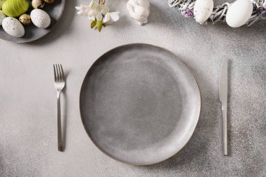 Gri tabaklı Paskalya bayramı sofrası, bahar çiçekleri ve yeşil renkli yumurtalar..