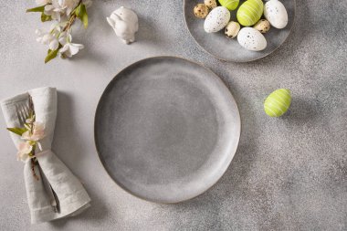 Gri tabaklı Paskalya bayramı sofrası, bahar çiçekleri ve yeşil renkli yumurtalar..