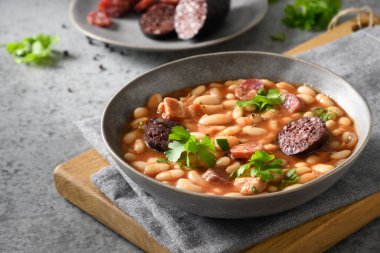 İspanyol asturiana fabada ile sucuk ve morcilla ile gri arka planda.