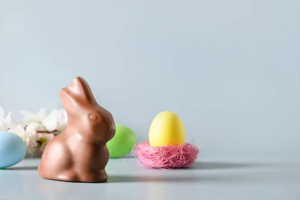 Uovo rosa pasquale e coniglietto al cioccolato in composizione primaverile su azzurro. — Foto Stock