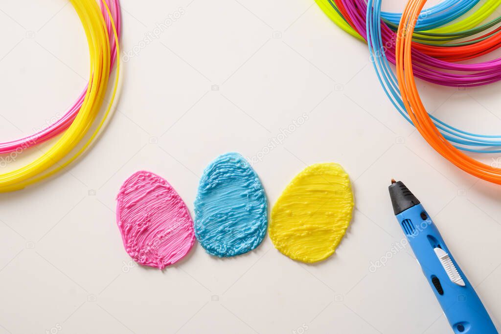Creative colorful eggs of popular plastic for Easter holiday. Rainbow plastic filaments with 3D pen laying on white background. New toy for child. Top view