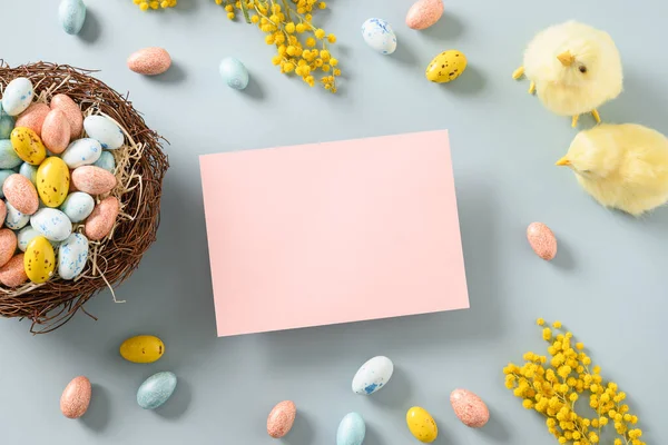 Rosa de Pascua en blanco para saludos con pollitos amarillos, huevos de chocolate, flores. — Foto de Stock