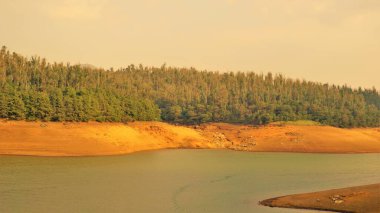 Günbatımında Pykara Gölü, Ooty, Tamilnadu 'nun güzel manzarası. Gökyüzü manzarası, su, gün batımı ve tekne yolculuğundan görülebilen yeşil çalılar. Güney Hindistan 'daki en iyi balayı yeri..