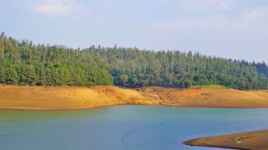 Günbatımında Pykara Gölü, Ooty, Tamilnadu 'nun güzel manzarası. Gökyüzü manzarası, su, gün batımı ve tekne yolculuğundan görülebilen yeşil çalılar. Güney Hindistan 'daki en iyi balayı yeri..