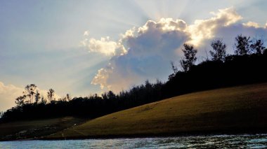 Günbatımında Pykara Gölü, Ooty, Tamilnadu 'nun güzel manzarası. Gökyüzü manzarası, su, gün batımı ve tekne yolculuğundan görülebilen yeşil çalılar. Güney Hindistan 'daki en iyi balayı yeri..