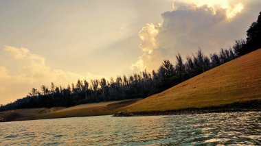 Günbatımında Pykara Gölü, Ooty, Tamilnadu 'nun güzel manzarası. Gökyüzü manzarası, su, gün batımı ve tekne yolculuğundan görülebilen yeşil çalılar. Güney Hindistan 'daki en iyi balayı yeri..