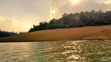 Günbatımında Pykara Gölü, Ooty, Tamilnadu 'nun güzel manzarası. Gökyüzü manzarası, su, gün batımı ve tekne yolculuğundan görülebilen yeşil çalılar. Güney Hindistan 'daki en iyi balayı yeri..