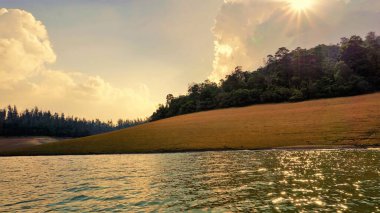 Günbatımında Pykara Gölü, Ooty, Tamilnadu 'nun güzel manzarası. Gökyüzü manzarası, su, gün batımı ve tekne yolculuğundan görülebilen yeşil çalılar. Güney Hindistan 'daki en iyi balayı yeri..