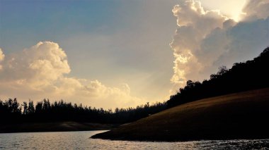Günbatımında Pykara Gölü, Ooty, Tamilnadu 'nun güzel manzarası. Gökyüzü manzarası, su, gün batımı ve tekne yolculuğundan görülebilen yeşil çalılar. Güney Hindistan 'daki en iyi balayı yeri..