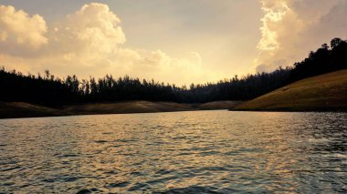 Günbatımında Pykara Gölü, Ooty, Tamilnadu 'nun güzel manzarası. Gökyüzü manzarası, su, gün batımı ve tekne yolculuğundan görülebilen yeşil çalılar. Güney Hindistan 'daki en iyi balayı yeri..