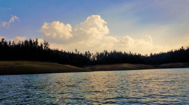 Günbatımında Pykara Gölü, Ooty, Tamilnadu 'nun güzel manzarası. Gökyüzü manzarası, su, gün batımı ve tekne yolculuğundan görülebilen yeşil çalılar. Güney Hindistan 'daki en iyi balayı yeri..