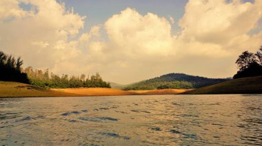 Günbatımında Pykara Gölü, Ooty, Tamilnadu 'nun güzel manzarası. Gökyüzü manzarası, su, gün batımı ve tekne yolculuğundan görülebilen yeşil çalılar. Güney Hindistan 'daki en iyi balayı yeri..