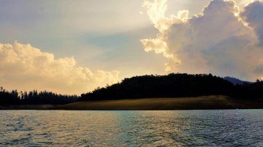 Günbatımında Pykara Gölü, Ooty, Tamilnadu 'nun güzel manzarası. Gökyüzü manzarası, su, gün batımı ve tekne yolculuğundan görülebilen yeşil çalılar. Güney Hindistan 'daki en iyi balayı yeri..