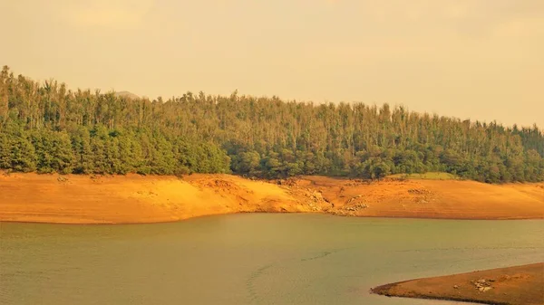 Günbatımında Pykara Gölü, Ooty, Tamilnadu 'nun güzel manzarası. Gökyüzü manzarası, su, gün batımı ve tekne yolculuğundan görülebilen yeşil çalılar. Güney Hindistan 'daki en iyi balayı yeri..